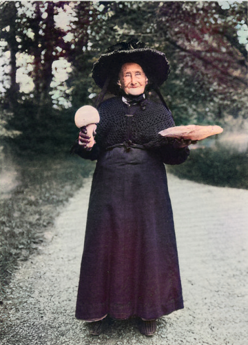 Elder Millennials: Watching the World End, Over and Over An old woman holds up two giant mushrooms